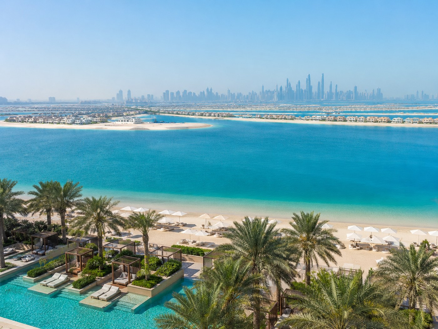 Beachfront resort view across Palm Jumeirah with blue water and palm trees.